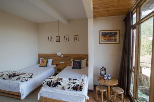 - une chambre avec 2 lits, une table et une fenêtre dans l'établissement Flowers Residence, à Yuanyang