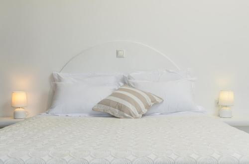 a white bed with white pillows and a striped pillow at Casa Borealis in Naxos Chora