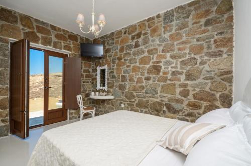 a bedroom with a bed and a stone wall at Casa Borealis in Naxos Chora
