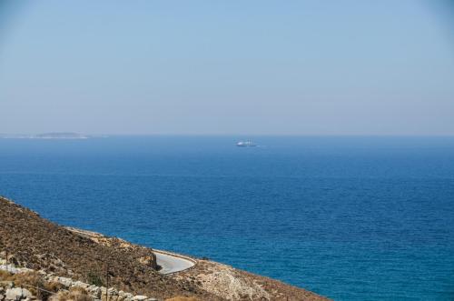 a road leading to the ocean with a ship in the distance at Casa Borealis in Naxos Chora