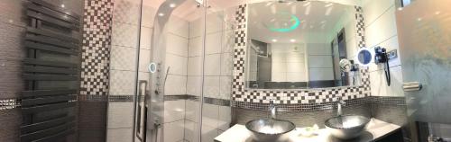a bathroom with two sinks and a shower with a mirror at MenDan Magic Spa & Wellness Hotel in Zalakaros