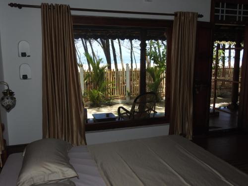 um quarto com uma cama e uma grande janela em Alleppey Beach Garden em Alappuzha