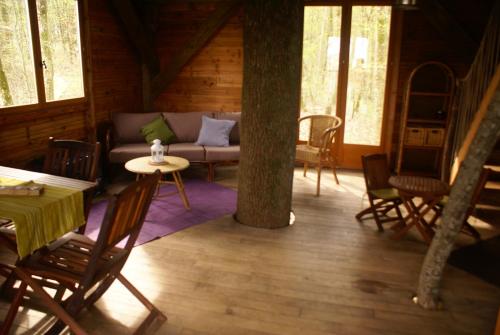 a living room with a couch and chairs in a cabin at Le Chêne Perché in Signy-lʼAbbaye