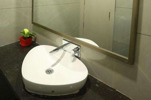a white sink in a bathroom with a mirror at Samyukta resort in Gogāpur