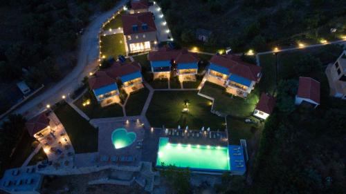 an aerial view of a house with a swimming pool at night at Thesmos Village in Mýtikas