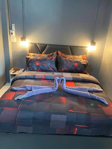 a bed with a blanket on top of it at Phunara Guest House in Phatthalung