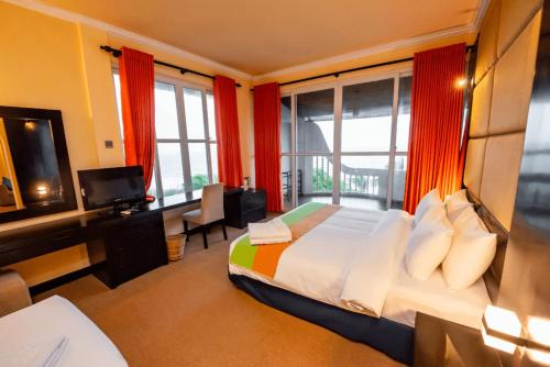 a bedroom with a bed and a desk and windows at Peacock Beach Resort- Hambantota in Hambantota