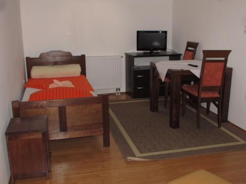 a bedroom with a bed and a table and a desk at Smještaj Slavonija in Daruvar
