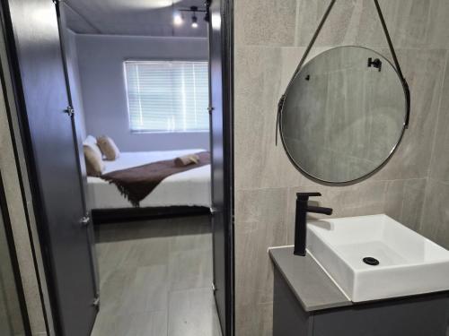 a bathroom with a sink and a mirror and a bed at Coastal Cove in Cape Town