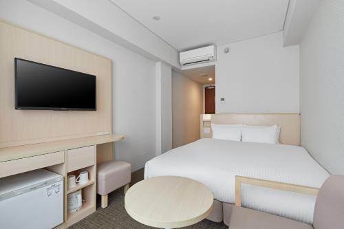 a hotel room with a bed and a tv at Sotetsu Fresa Inn Kyoto-Hachijoguchi in Kyoto