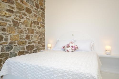 a bedroom with a white bed with a stone wall at Casa Borealis in Naxos Chora