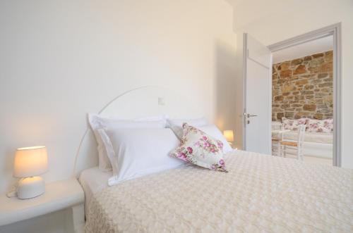 a white bedroom with a bed with two pillows at Casa Borealis in Naxos Chora