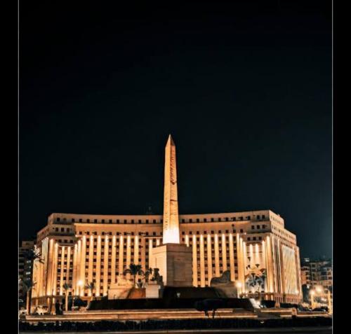 a large building with a large obelisk in front of it at The Egyptian apartment in Cairo