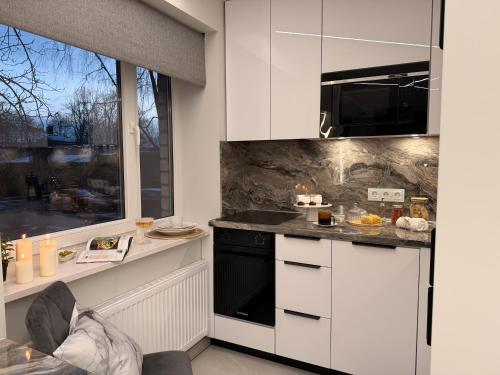 a kitchen with white cabinets and a black appliance at JE downtown suite in Jelgava