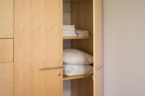 a cupboard with a stack of towels and a pillow at Hotel Uusikuu in Mikkeli