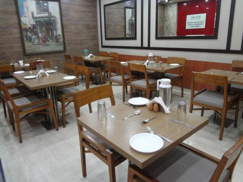 a dining room with wooden tables and chairs in a restaurant at Royal Park Hotel Dockyard in Mumbai