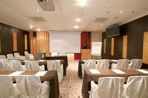 a conference room with tables and chairs and a screen at Hotel Hullu Poro in Levi