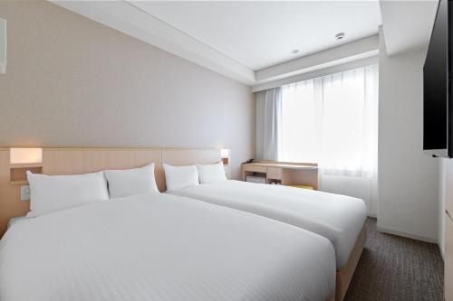 a large white bed in a room with a window at Sotetsu Fresa Inn Kyoto-Hachijoguchi in Kyoto