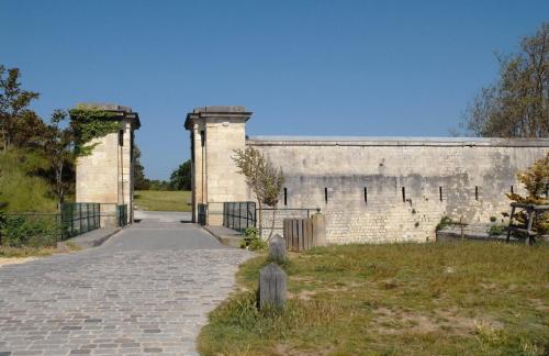 an old brick wall with a gate and a walkway at Hotel Napoleon in Île dʼAix