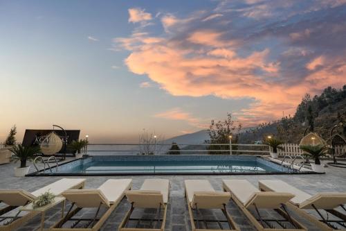 una piscina con tumbonas y una puesta de sol en Echor KC Grand Kufri, en Fagu