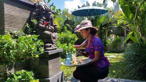 a woman holding a plate of food in a garden at Ubud Paradise Villa in Ubud