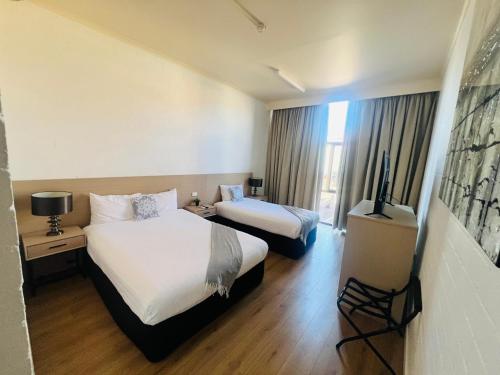 a hotel room with two beds and a flat screen tv at Pavilion Hotel Wagga Wagga in Wagga Wagga