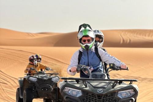 two people riding on a quad bike in the desert at Experience Luxury Desert Camp in Merzouga