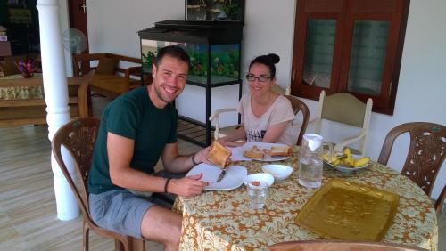 a man and woman sitting at a table eating food at Yuthika Resort in Negombo