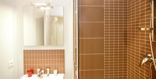 La salle de bains est pourvue d'une douche, d'un lavabo et d'un miroir. dans l'établissement Appart' Lyonnais, à Lyon