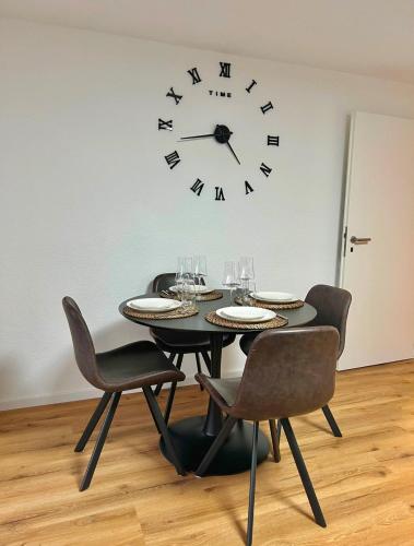 una mesa negra con sillas y un reloj en la pared en Ferienwohnung Südwind, en Hohentengen