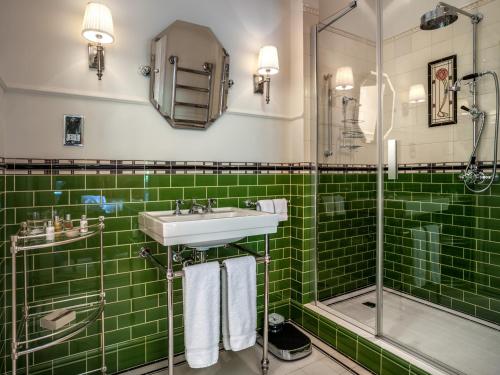 een groene betegelde badkamer met een wastafel en een douche bij Pałac Ciekocinko Hotel Resort & Wellness in Ciekocinko