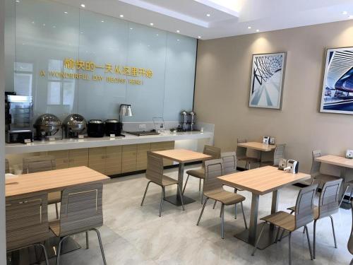 City Comfort Inn Wuhan Rui'an Street Metro Station في ووهان: مطعم به طاولات وكراسي خشبية ومنضدة