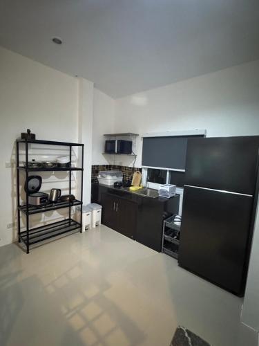 a kitchen with black cabinets and a black refrigerator at Pattiya House in Hua Thanon Beach