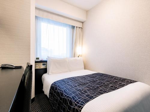 a hotel room with a bed and a window at APA Hotel Higashi Umeda Minami Morimachi Ekimae in Osaka