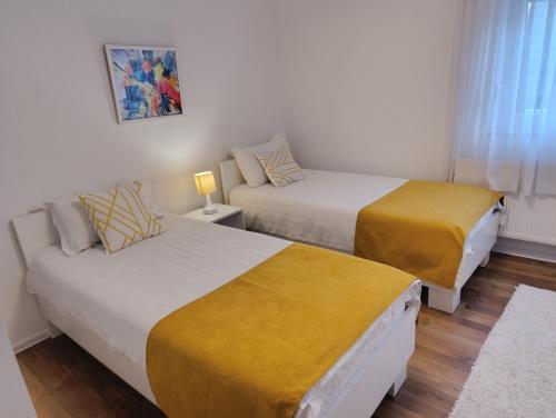 - une chambre avec 2 lits et des couvertures jaunes dans l'établissement Apartmani Jasmina 2, à Bihać