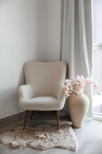 a chair and a vase with flowers in a room at Desert Retreat Canal View walk to F1 Yas Island in Abu Dhabi
