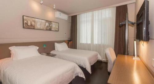 a hotel room with two beds and a television at Jinjiang Inn Select Qingdao West Coast Coach Exhibition Center High-Speed Railway Station in Huangdao