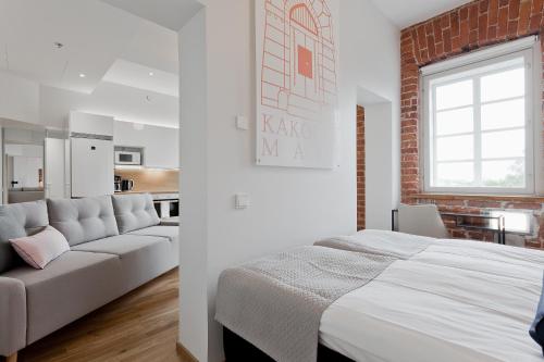 - une chambre avec un lit blanc et un canapé blanc dans l'établissement Forenom Serviced Apartments Turku Kakolanmäki, à Turku