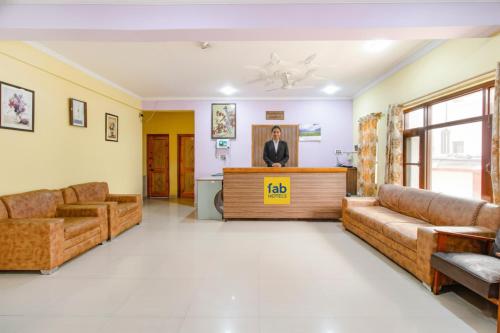 a lobby with couches and a woman standing at the podium at FabHotel Grand Comforts in Haidarpur