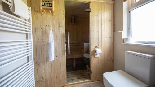 a bathroom with a wooden wall with a shower and a toilet at Primrose 2 bed-No Pets-Daisy in Horham