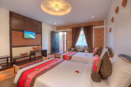 a hotel room with two beds and a television at Kravan Siem Reap Boutique Villa in Phumĭ Kruŏs