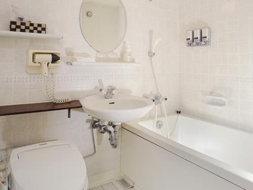 a bathroom with a sink and a toilet and a bath tub at Hotel Emisia Sapporo in Sapporo