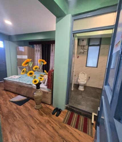a bathroom with a toilet and a vase of flowers at Sonali Megh in Darjeeling