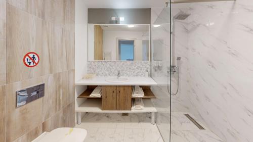 een badkamer met een wastafel en een glazen douche bij Royal Hotel & Events in Băileşti