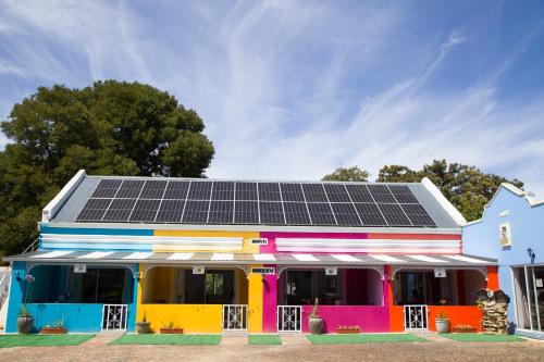 Un edificio colorido con paneles solares en el techo. en Storms River Self Catering Apartments, en Stormsrivier