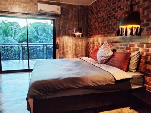 a bedroom with a bed and a brick wall at Baan Malee Villa in Ko Lanta