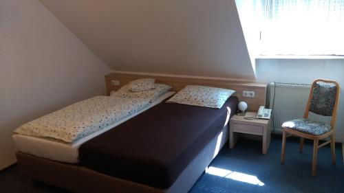 a small bedroom with a bed and a chair at Gasthaus Pension Rezatgrund in Windsbach