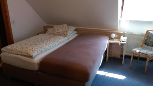 a small bedroom with a bed and a chair at Gasthaus Pension Rezatgrund in Windsbach
