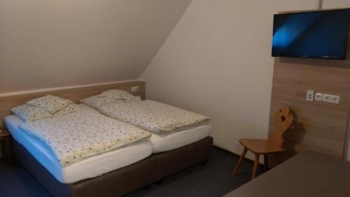 a small bedroom with two beds and a flat screen tv at Gasthaus Pension Rezatgrund in Windsbach