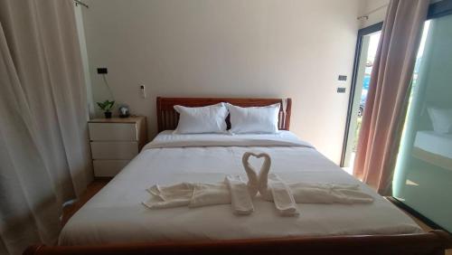 a bed with white towels on it with a window at ธัญญ์ รีสอร์ท หินดาด in Ban Pak Nam Chumphon